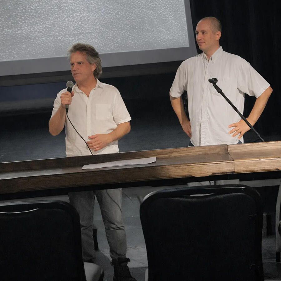 Silver City, New Mexico filmmaker Max Nealon (left) introduces his documentary, Blue Oasis: The Life & Art of Toney Chavez, at the 3rd annual Royale Film Festival, hosted by Danny Hercules (right). (Photo by Linda Hicks. Enhanced by Cherry.)